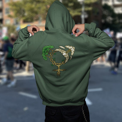 Person wearing a bottle green hoodie with a tree design on the back, standing in an urban setting. A women's rights hoodie design that pays homage to women and promotes social awareness of how most destructive elements of humankind come from men. Women create life, men destroy it. Comfortable and practical. It's extra soft and has a convenient front pouch pocket. Made from organic cotton and recycled polyester, this women's rights hoodie is a great eco-friendly choice.