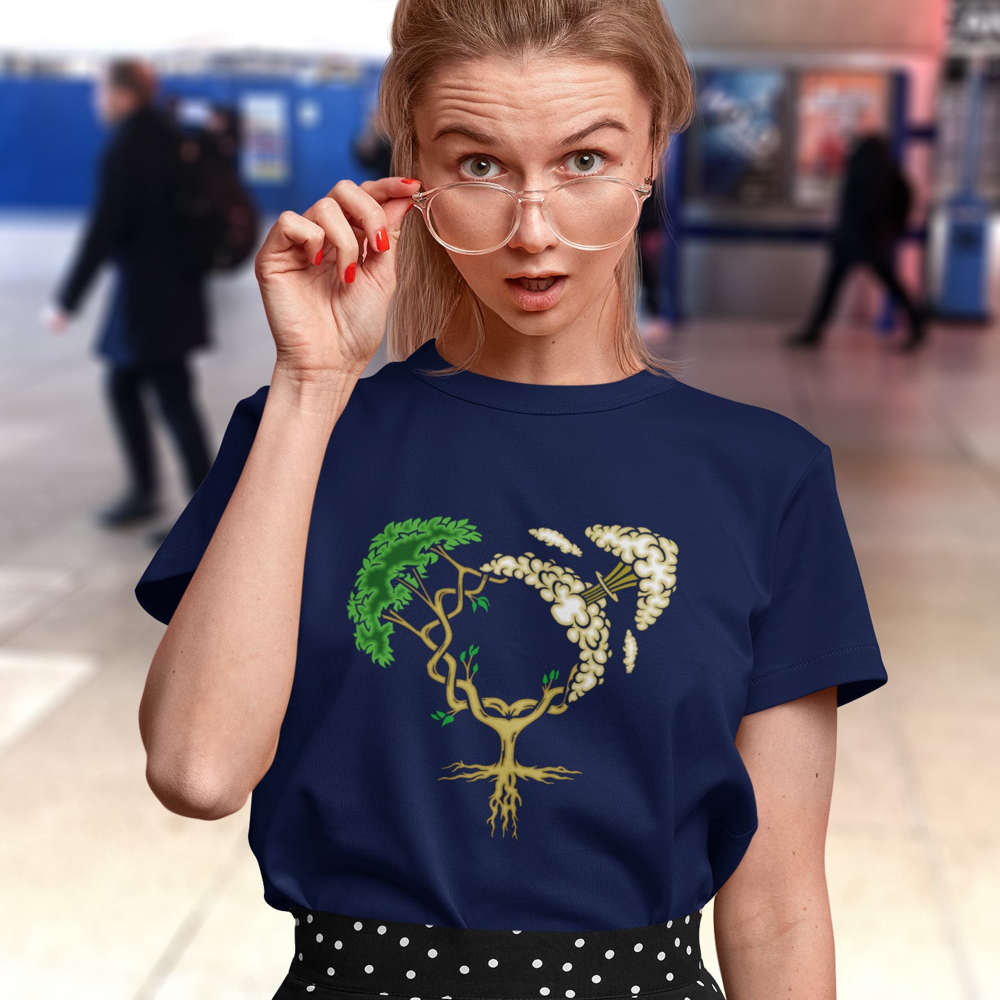 Woman wearing a  French navy blue t-shirt with a heart design featuring a tree and flowers, standing in a blurred indoor background. A women's rights t-shirt design that pays homage to women and promotes social awareness of how most destructive elements of humankind come from men. Women create life, men destroy it. Made from 100% organic ring-spun cotton, this women power t-shirt is unisex, high-quality, super comfy, and best of all, eco-friendly.