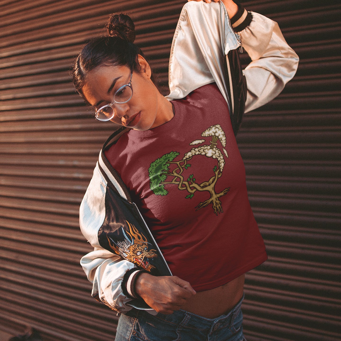 Person wearing a burgundy shirt with tree design and beige jacket against a brown corrugated background. A women's rights t-shirt design that pays homage to women and promotes social awareness of how most destructive elements of humankind come from men. Women create life, men destroy it. Made from 100% organic ring-spun cotton, this women power t-shirt is unisex, high-quality, super comfy, and best of all, eco-friendly.