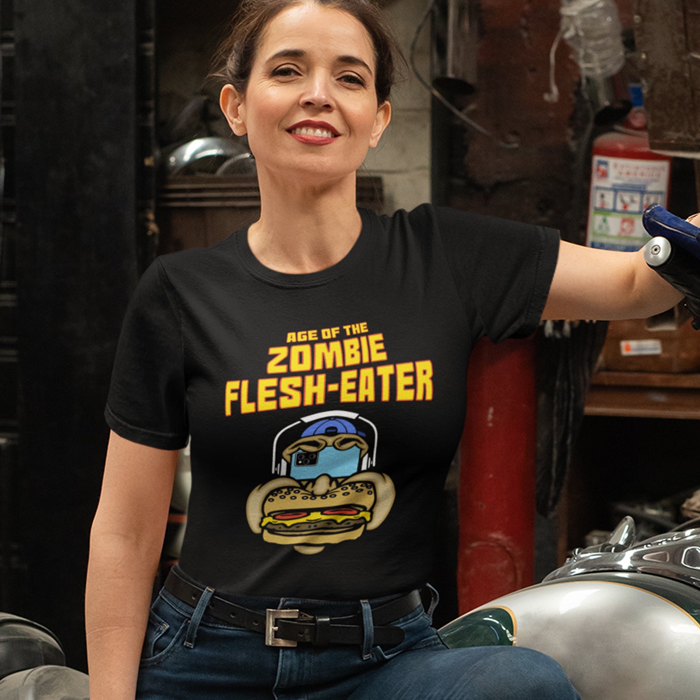 Woman wearing a black t-shirt with a graphic design and text, sitting on a motorcycle. This meat free t-shirt design plays on the interpretation of a late 70's B rate movie. As a modern day vegan surrounded by people hypnotised on their mobile phone while eating meat based fast food, you may be forgiven for thinking you are living in the age of the zombie flesh-eater. Made from 100% organic ring-spun cotton, this meat free t shirt design is unisex, high-quality, super comfy, and best of all, eco-friendly.