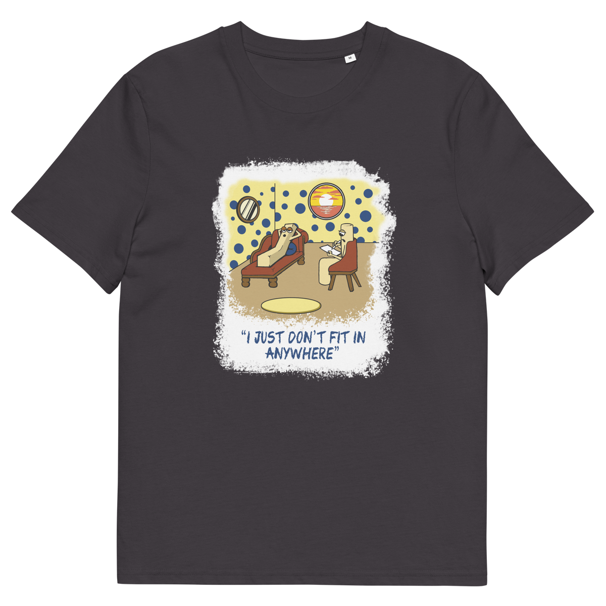 An anthracite grey short-sleeve t-shirt with a central graphic print. The graphic features a cartoon illustration of a person sitting on a lounge chair in a theorists room , with a white distressed border and the text 'I JUST DON'T FIT IN ANYWHERE' below.