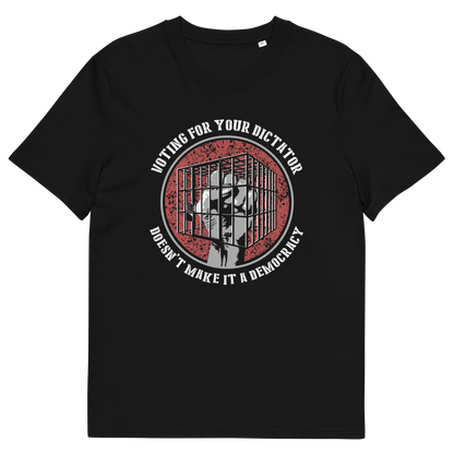 A black short-sleeve crewneck t-shirt with a circular graphic on the chest. The graphic features a red distressed background with a white silhouette of a person behind bars, surrounded by the text 'VOTING FOR YOUR DICTATOR DOESN'T MAKE IT A DEMOCRACY' in white.