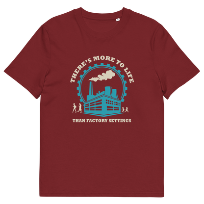 A burgundy short-sleeve crewneck t-shirt with a graphic print on the front. The graphic features a light blue and cream illustration of a factory with smokestacks, surrounded by the text 'THERE'S MORE TO LIFE THAN FACTORY SETTINGS'.