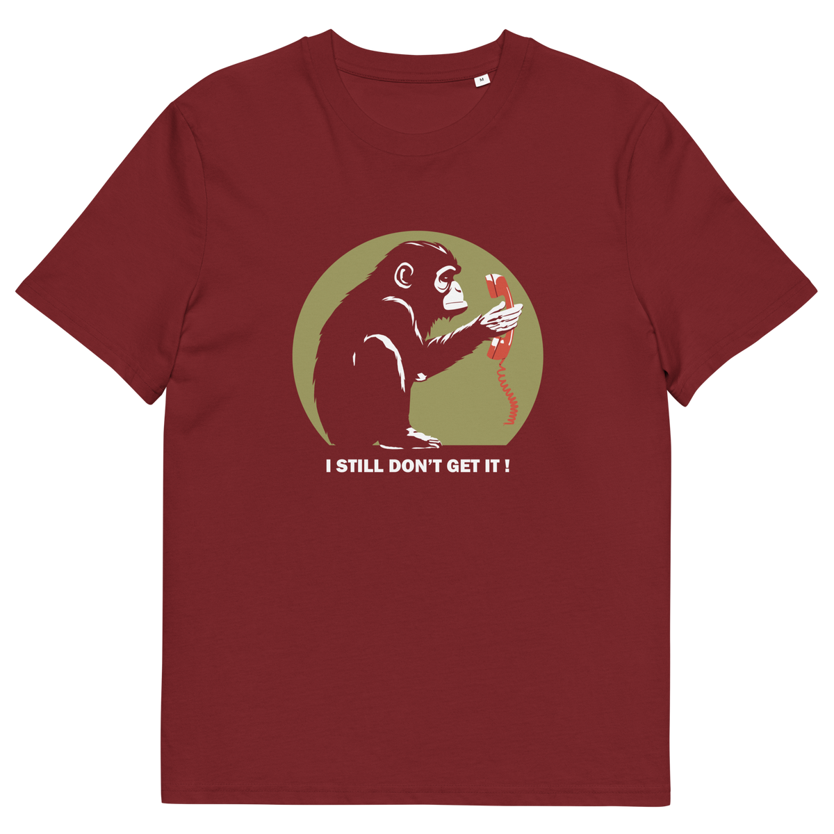 A burgundy t-shirt with a design of a monkey staring at an old style telephone receiver with text underneath saying "I STILL DON'T GET IT".