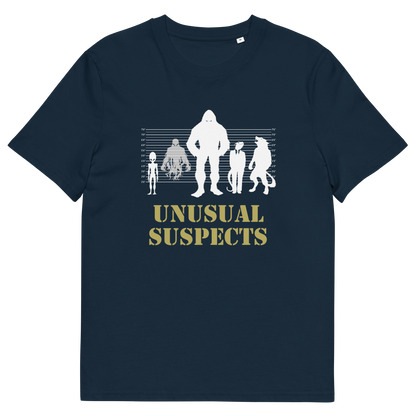 A French navy blue short-sleeve crewneck t-shirt with a graphic on the chest showing white silhouettes of various creatures against a height line up chart, with the text 'UNUSUAL SUSPECTS' printed below in a muted gold color.