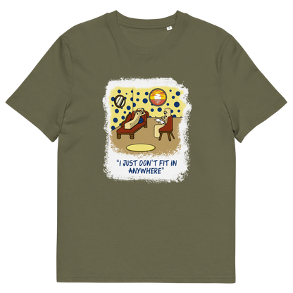 An khaki green short-sleeve t-shirt with a central graphic print. The graphic features a cartoon illustration of a person sitting on a lounge chair in a theorists room , with a white distressed border and the text 'I JUST DON'T FIT IN ANYWHERE' below.