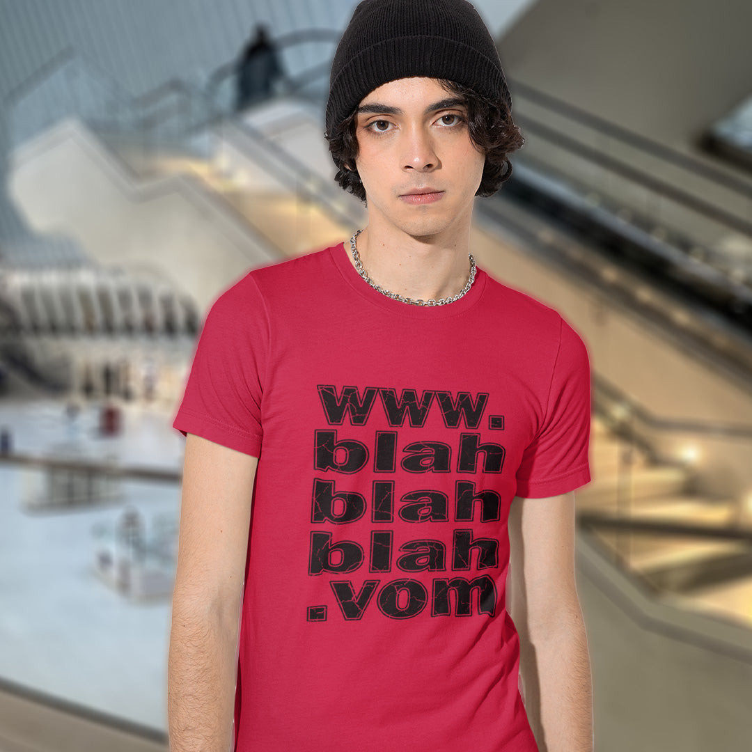 A man in a hat, standing in a shopping centre, wearing a red t-shirt with "www.blahblahblah.vom" text design.
